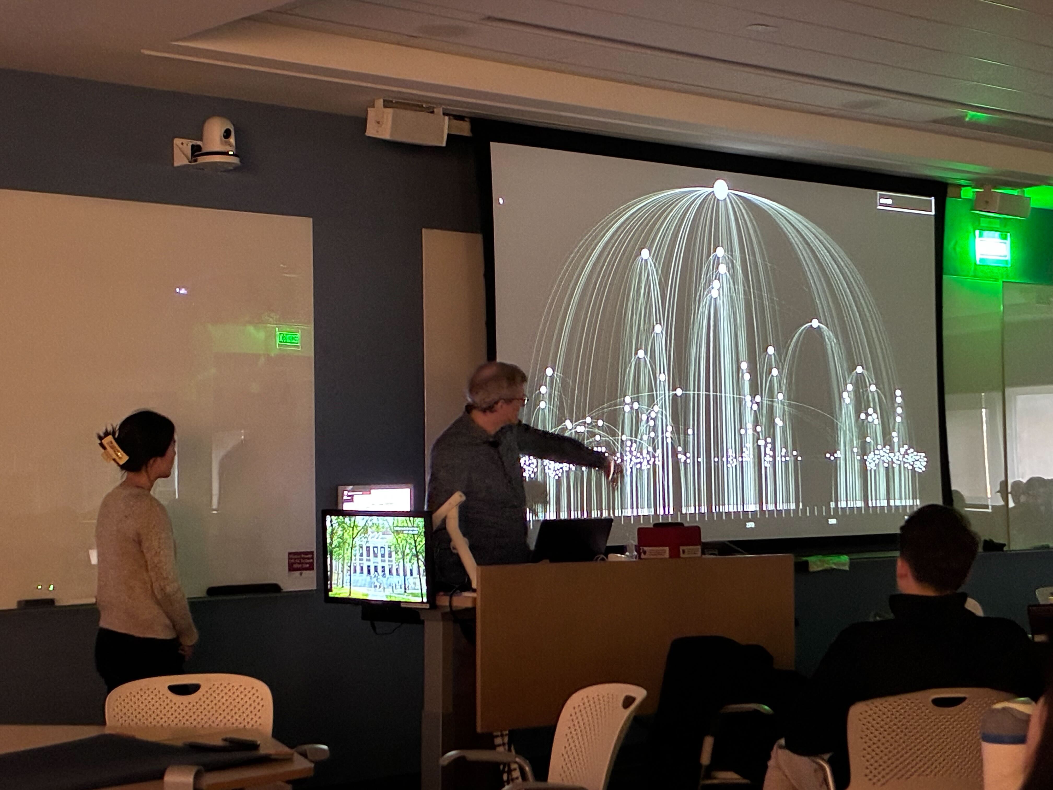 Mark standing in front of a large projected image of an early draft of our Miles Davis project explaining it to a class of students.